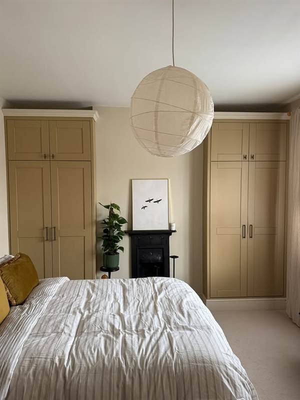 Fitted olive-green shaker wardrobes either side of a bedroom fireplace