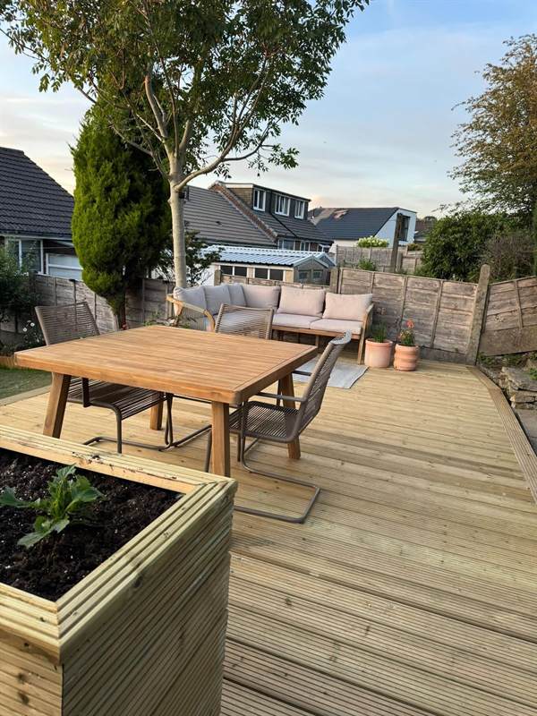 Timber garden decking with table, seating and a planter