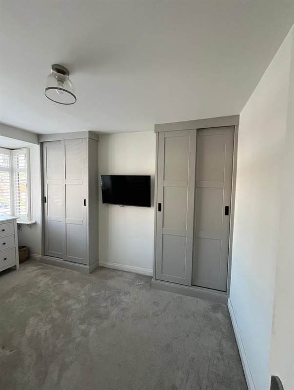 Grey sliding wardrobe doors either side of a wall-mounted TV