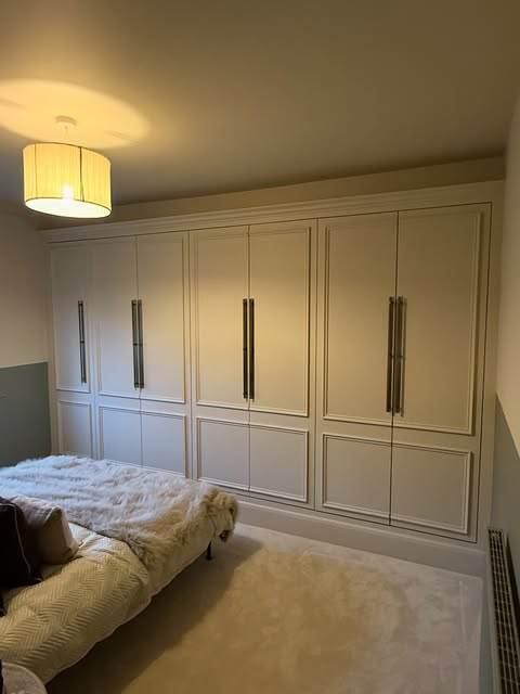 Cream sprayed fitted wardrobes with long brass bar handles