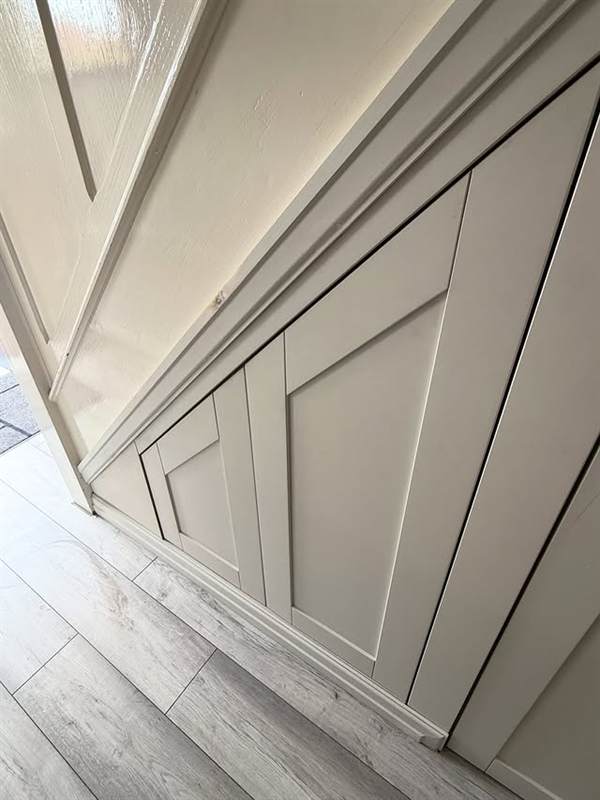 Primed under-stairs storage unit built around an awkward angled ceiling