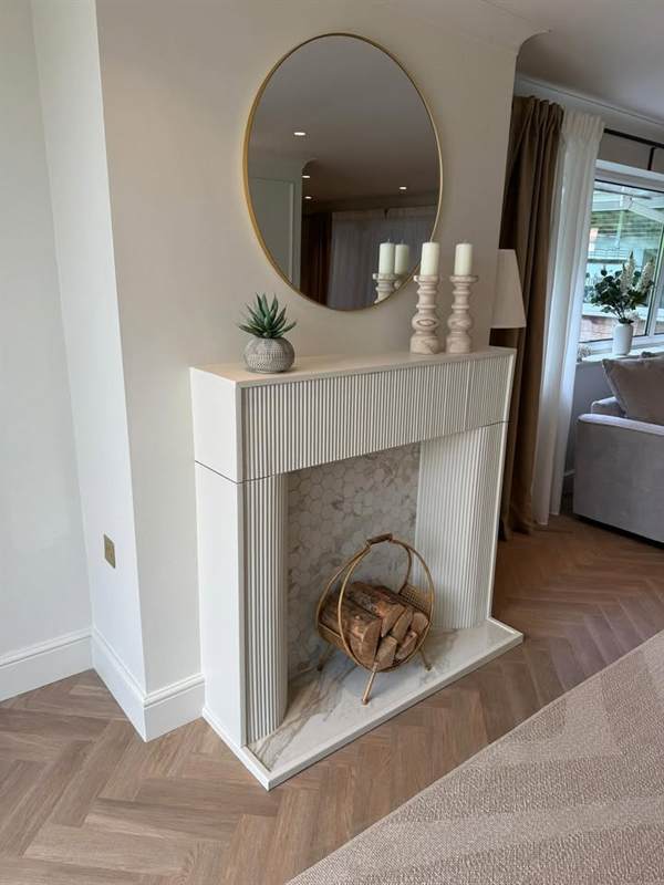 Fireplace surround with a curved fluted frame and marble hearth
