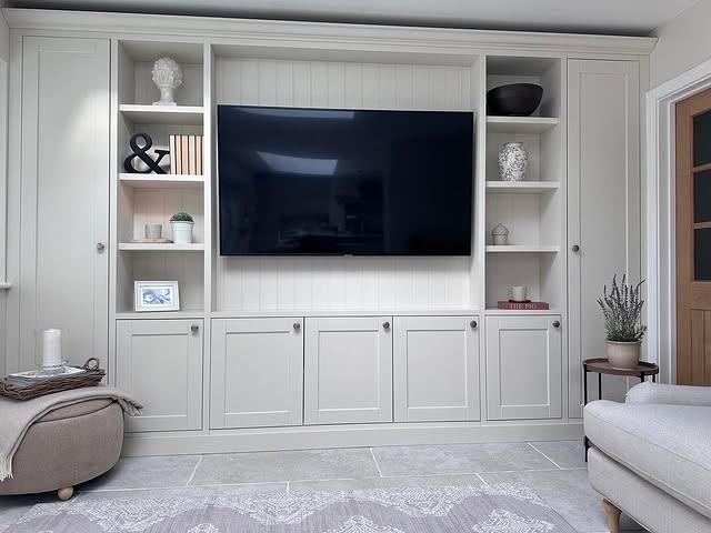 Built-in media unit with open shelving either side of a wall-mounted TV