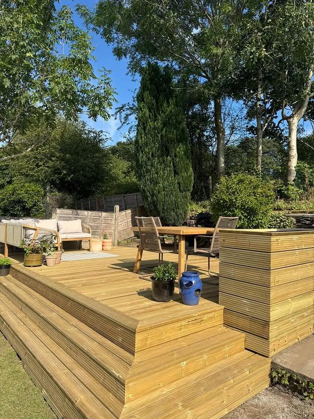 Timber garden decking with built-in steps, surrounded by trees